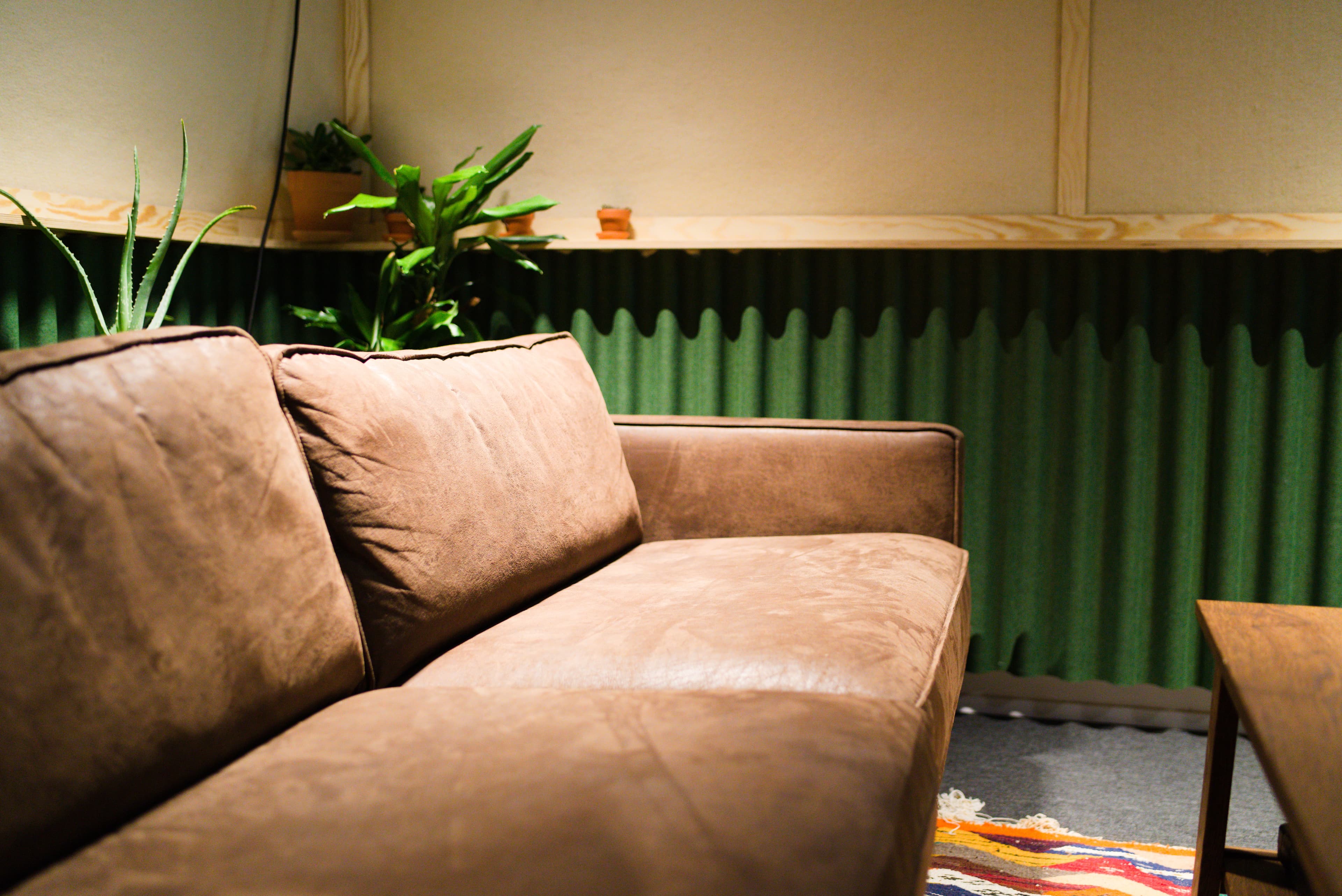Client lounge with leather sofa and green acoustic panels